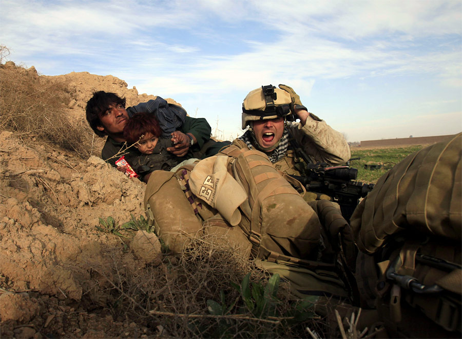 Младший капрал морской пехоты США Крис Сандерсон пытается защитить афганца и его дочь во время атаки талибов в городе Марджа в провинции Гильменд. © Goran Tomasevic/Reuters