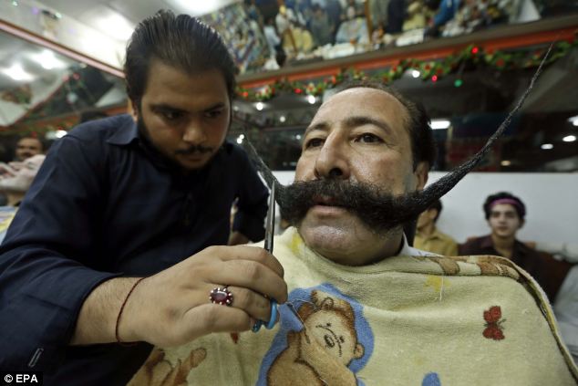 Pride in his appearance: Mr Afridi, pictured visiting a barber shop in Peshawar, Pakistan, spends 30minutes a day tending to his flowing moustache