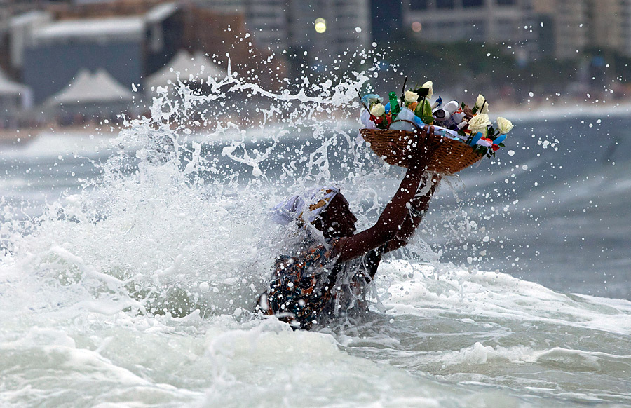 Бразильская верующая преподносит дар богине моря Йеманже в Рио-де-Жанейро. © Victor R. Caivano/AP Photo