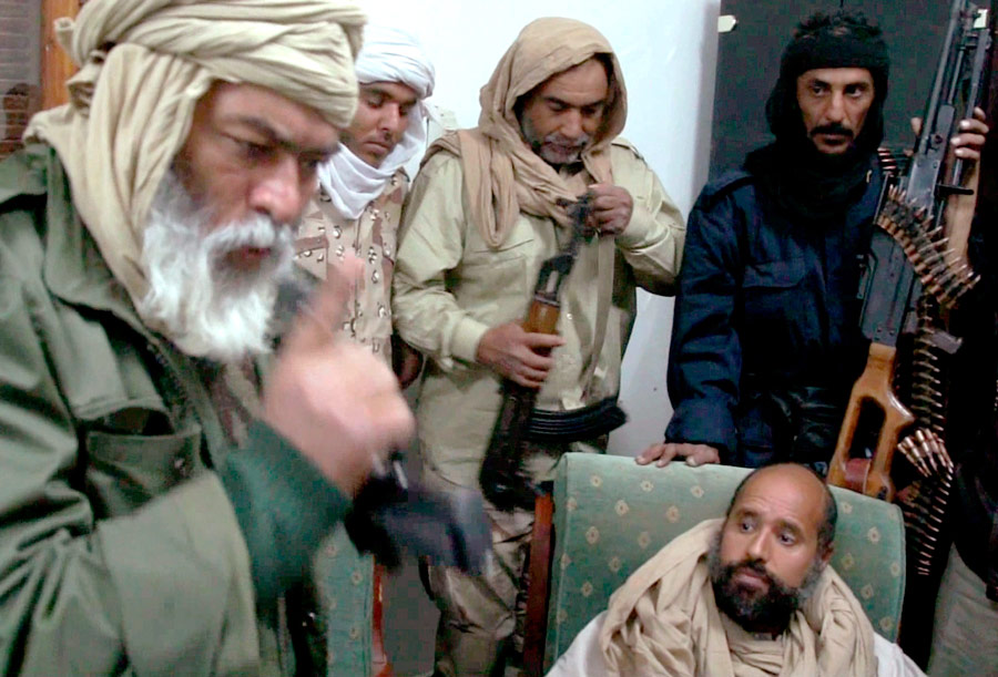 Cын покойного ливийского лидера Муамара Каддафи Сейф аль-Ислам (справа) в окружении поймавших его ливийцев. © АP Photo