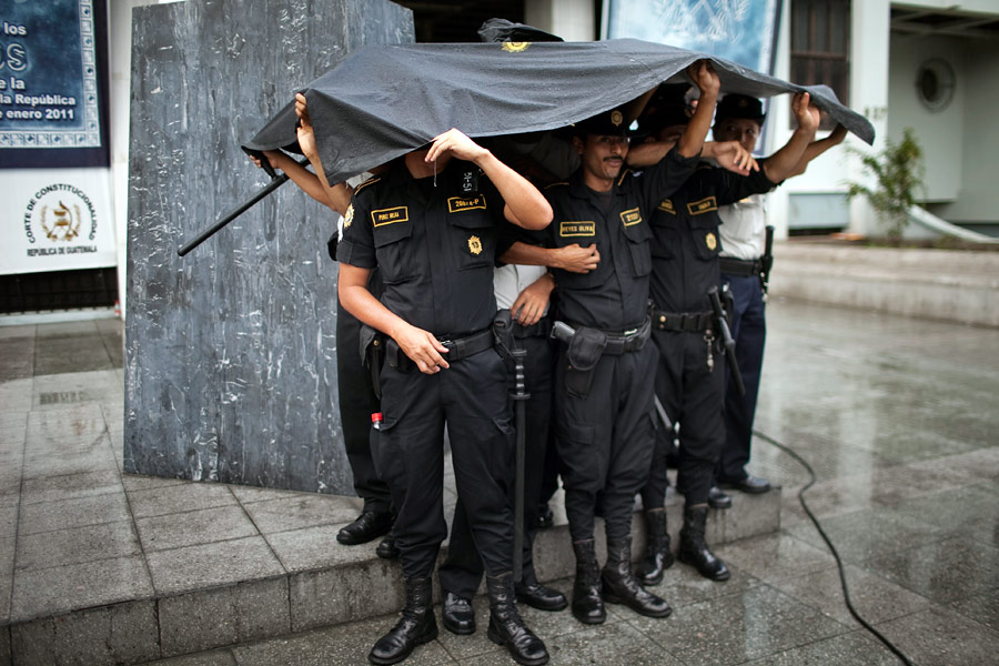 Гватемальские полицейские прячутся от дождя. © Rodrigo Abd/AP Photo