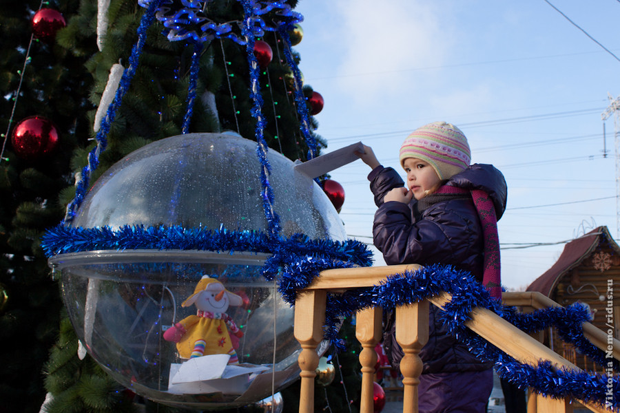 Девочка опускает письмо Деду Морозу в волшебный почтовый шар 