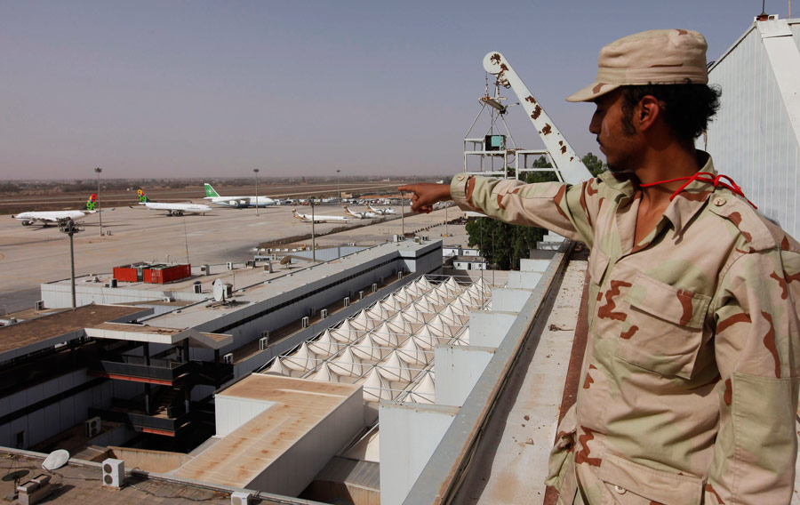 Солдат армии Переходного национального совета указывает на самолеты в международном аэропорту Триполи. © Ismail Zitouny/Reuters