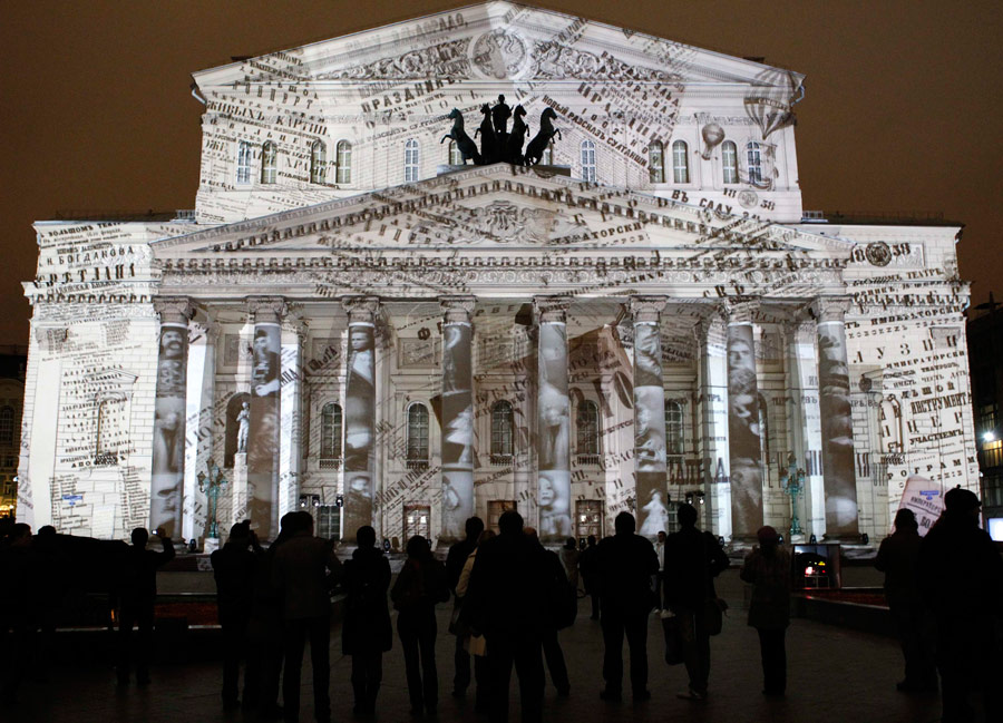 Люди смотрят на подсветку здания Большого театра. © Сергей Карпухин/Reuters