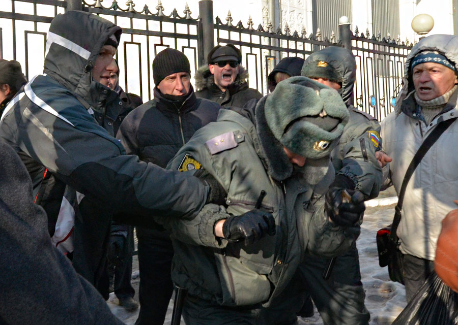 Сотрудник полиции пытается уклонится от группы митингующих на акции протеста «За честные выборы» во Владивостоке 24 декабря 2011 года. © Yuri Maltsev/Reuters