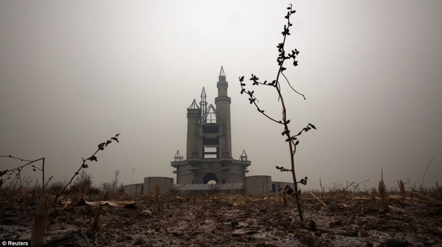 A grim-looking unfinished castle stands uncompleted in a field after funds were withdrawn due to disagreements with the local government and farmers