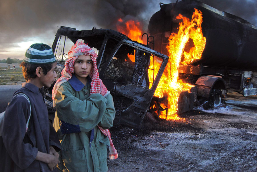 Школьники стоят возле горящих бензовозов в пакистанском районе Болан Белуджистан. © Amir Hussain/Reuters