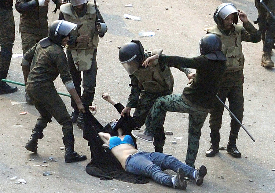 Полицейские избивают женщину в ходе столкновения с манифестантами в Каире. © Reuters
