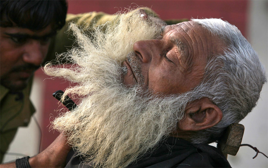 Индийский рикша приводит в порядок свою бороду у придорожного парикмахера на окраине Нью-Дели. © Parivartan Sharma/Reuters