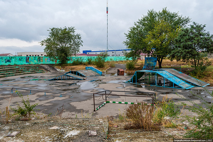 109. Так невинномысский скейт-парк выглядел в сентябре 2012 года: грязь и лужи, кучи мусора, прогнившие и поломанные рампы. На переднем плане — перевёрнутые футбольные ворота, на заднем — перевёрнутый мусорный контейнер.