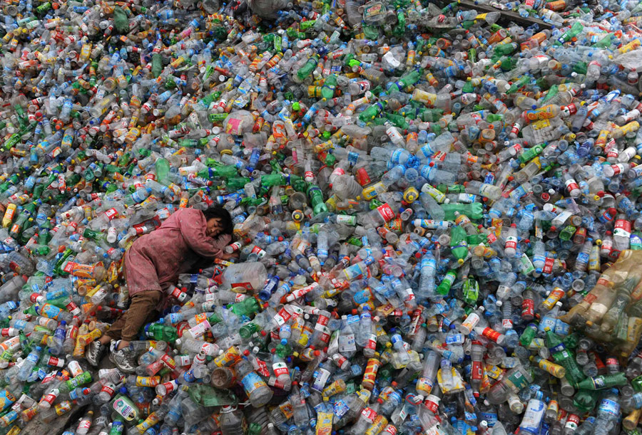 Рабочий китайского мусороперерабатывающего завода в Шеньжень спит, лежа на пластиковых бутылках. © Reuters
