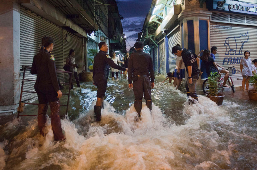 Полицейские ждут, чтобы оказать помощь пострадавшим от наводнения в чайнатауне в Бангкоке. © Adrees Latif/Reuters