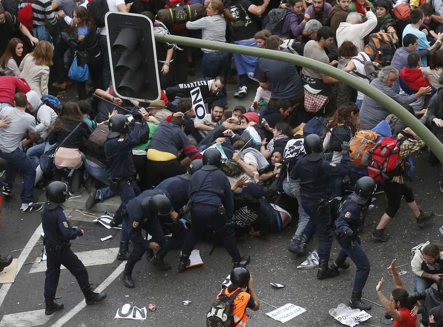 Испанский полицейский спецназ пытается остановить демонстрантов, прорывающихся к зданию парламента в Мадриде © REUTERS/Andrea Comas