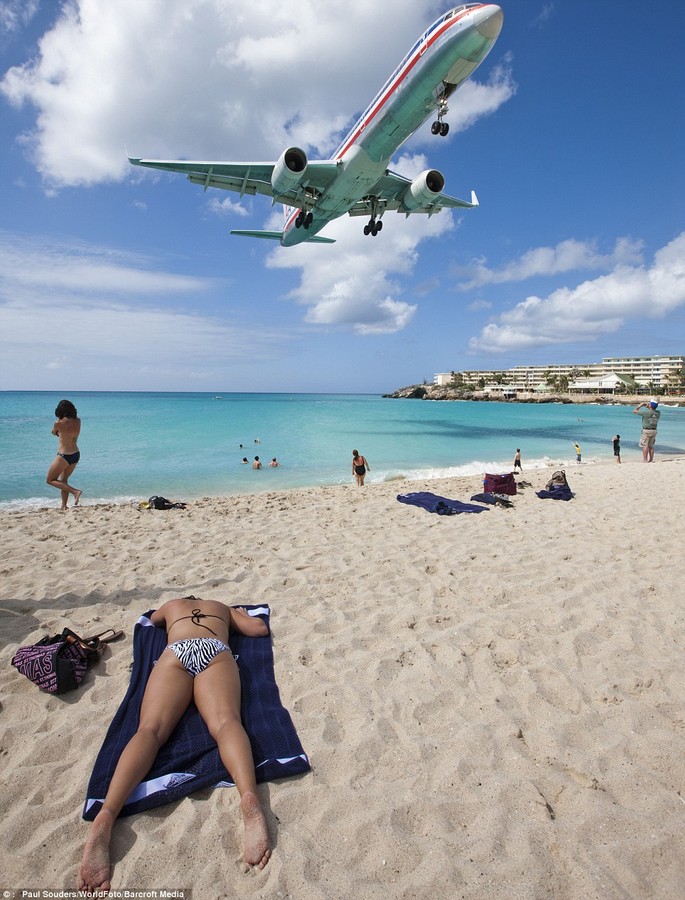 Noisy interruption: A jet on final approach above a young woman sunbathing at end of landing strip at Maho Beach of Princess Juliana International Airport 