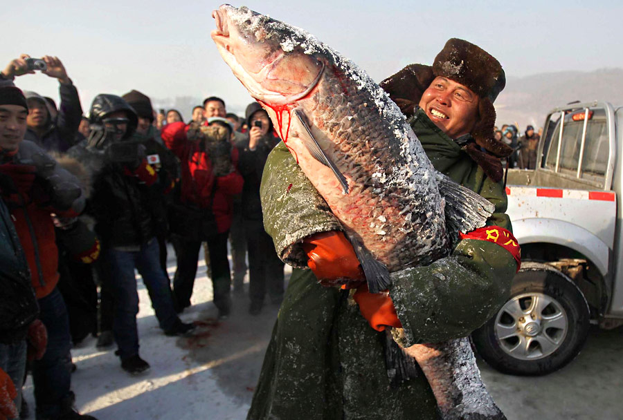 Китаец показывает самую большую рыбу, пойманную в ходе соревнования по зимней рыбалке в Чанчуне. © China Daily/Reuters