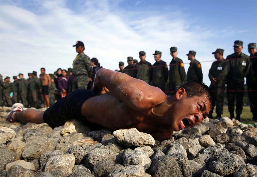 Кандидат в элитный отряд морской пехоты Тайваня ползет 50-метровую дистанцию по острым камням. © Nicky Loh/Reuters