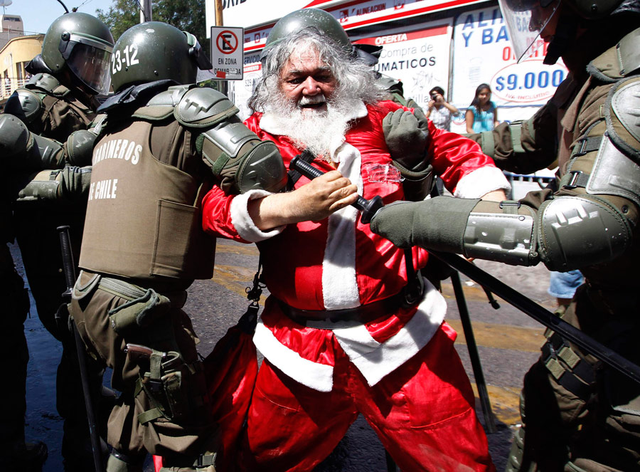 Полиция задерживает одного из протестантов, одетого в костюм Санта-Клауса, во время акции протеста студентов против существующей системы государственного образования в Сантьяго. © Ivan Alvarado/Reuters