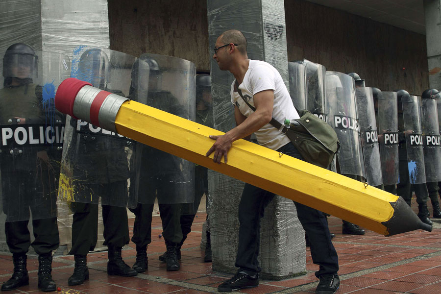 Колумбийский демонстрант пытается стереть полицейских ластиком. © FREDY BUILES/Reuters