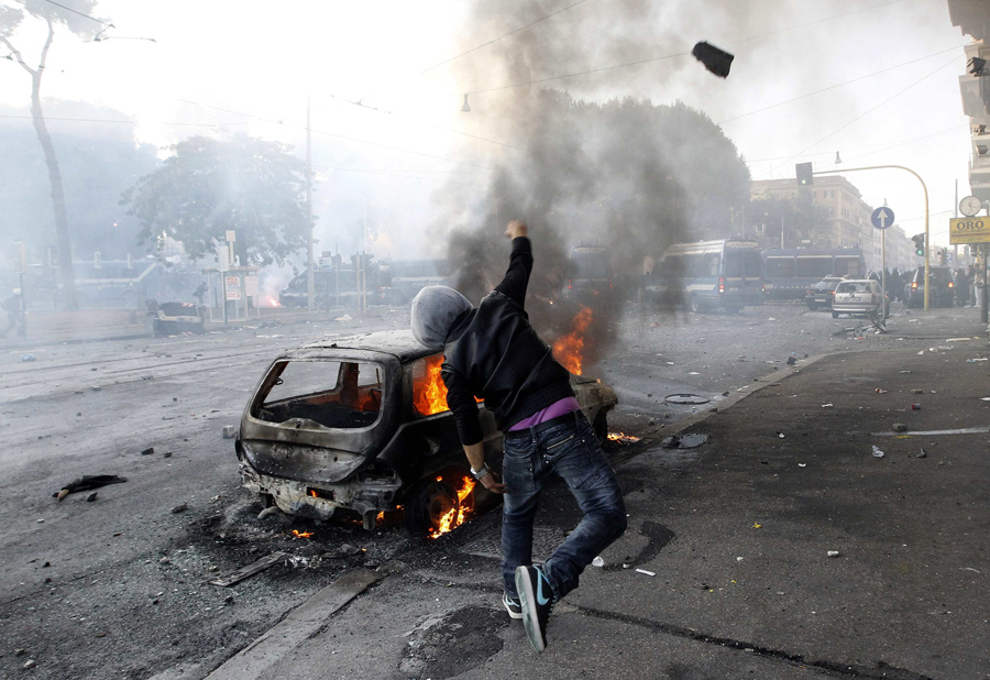 Демонстрант кидает камень в полицейских. © Alessandro Bianchi/Reuters