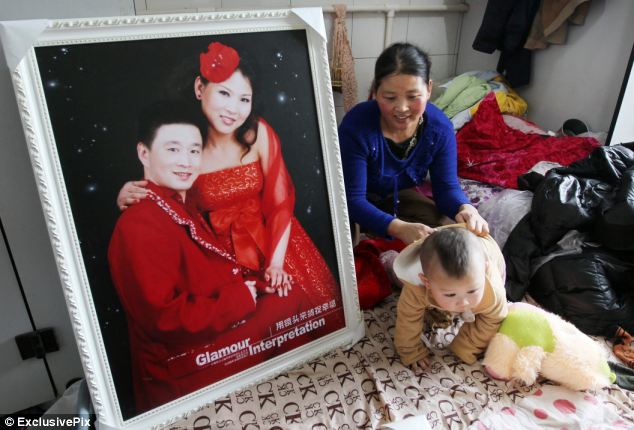 Wedded bliss: Ms Wang shows her son the couple's wedding photograph. Mr Zeng could not scrape together enough money for a real honeymoon, but took out 500 yuan from his savings and rented a 900-square-feet apartment in a high-end neighborhood