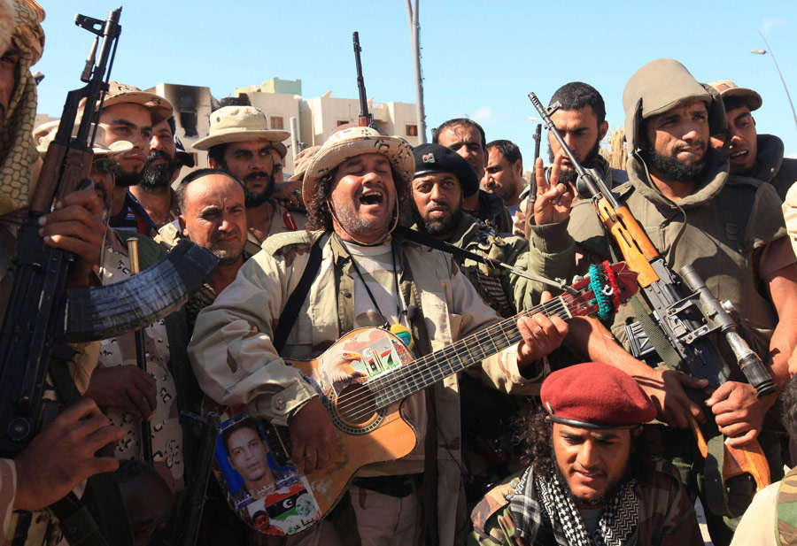 Ливийский музыкант Масод Аль-Басер развлекает отряд бойцов против режима Каддафи песнями. © Esam Al-Fetori/Reuters