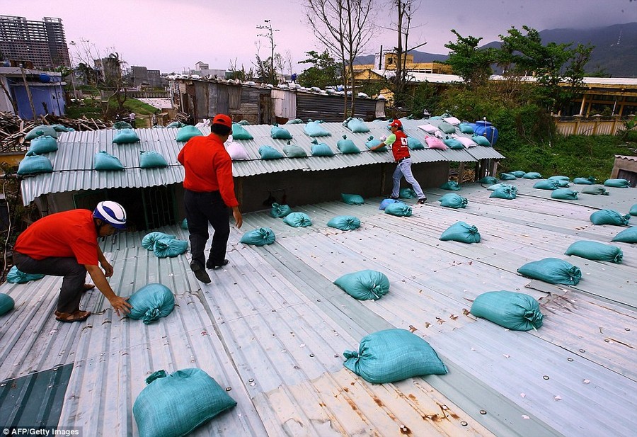 Workers: Local Red Cross staff place sand bags on the roof of a house in Danang, Vietnam 