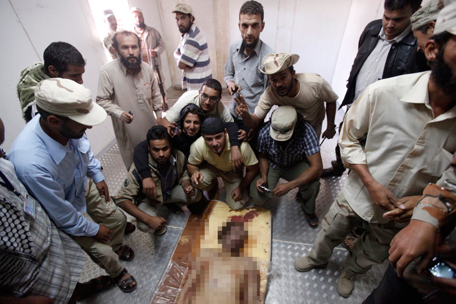 Тело убитого ливийского лидера Муаммара Каддафи в окружении повстанцев. © Saad Shalash/ Reuters