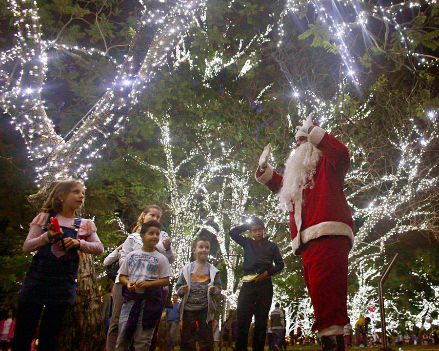 Мужчина в костюме Санта-Клауса развлекает детей возле наряженных новогодних елок в Сан-Паулу. © Nacho Doce/Reuters