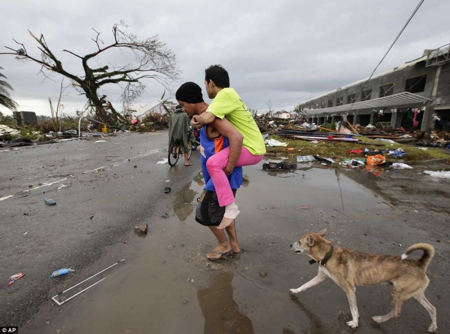 A man with an injured leg is carried through the devastation of former residential roads in Tacloban 