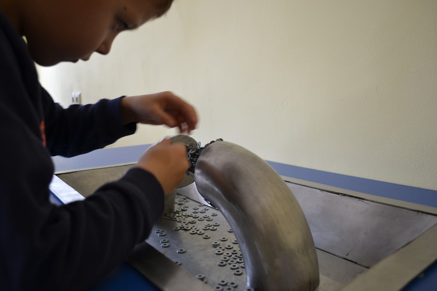 Мальчик увлеченно строит мост из металлических деталей, удерживаемых магнитным полем
