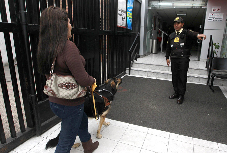 Охранник запрещает Джейн Косар войти в банк с собакой. © Mariana Bazo/Reuters