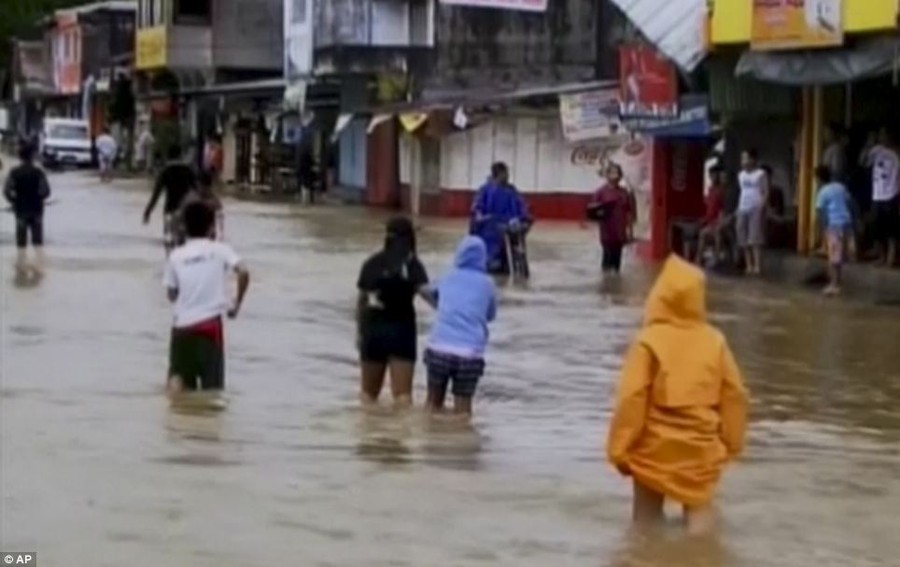 Under water: Residents wade through a flooded street in Mindoro, Philippines this morning following the typoon