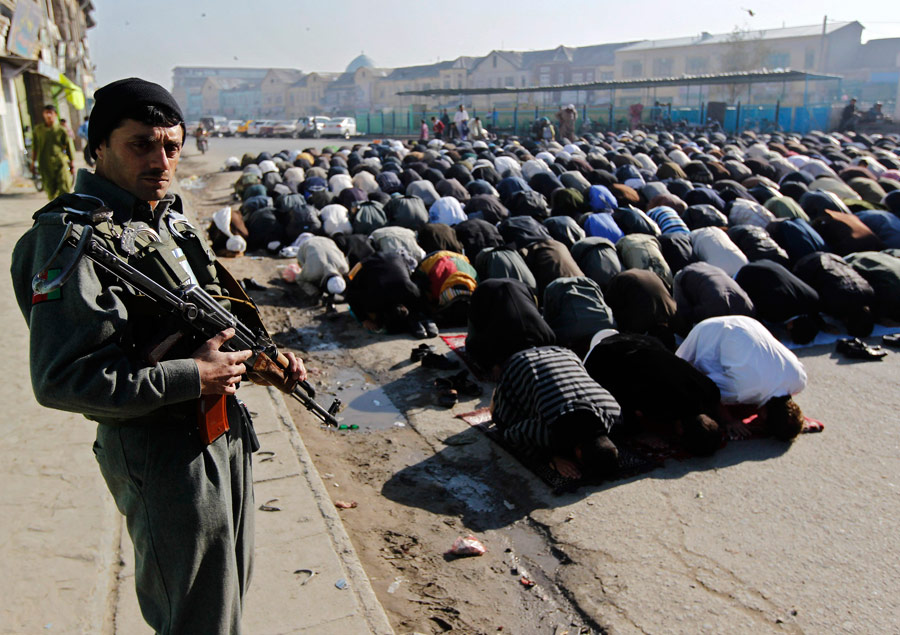 Афганский полицейский охраняет участников коллективного намаза в Кабуле. © Omar Sobhani/Reuters
