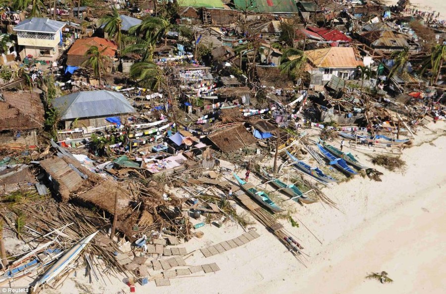 Badly hit: A group of houses in a coastal community in Iloilo Province, central Philippines, that have been destroyed. Boats lie thrown along the coastline also