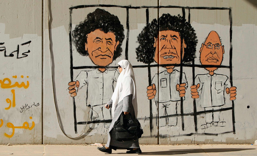 Граффити с изображением бывшего главы ливийской разведки Абдуллы аль-Сенусси (слева), бывшего ливийского лидера Муаммара Каддафи (в центре) и его сына Сейфа аль-Ислам Каддафи (справа) в Триполи. © Mohammed Salem/Reuters