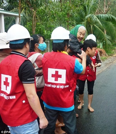 Assistance: An elderly woman is evacuated from her home by Red Cross staff in Vietnam