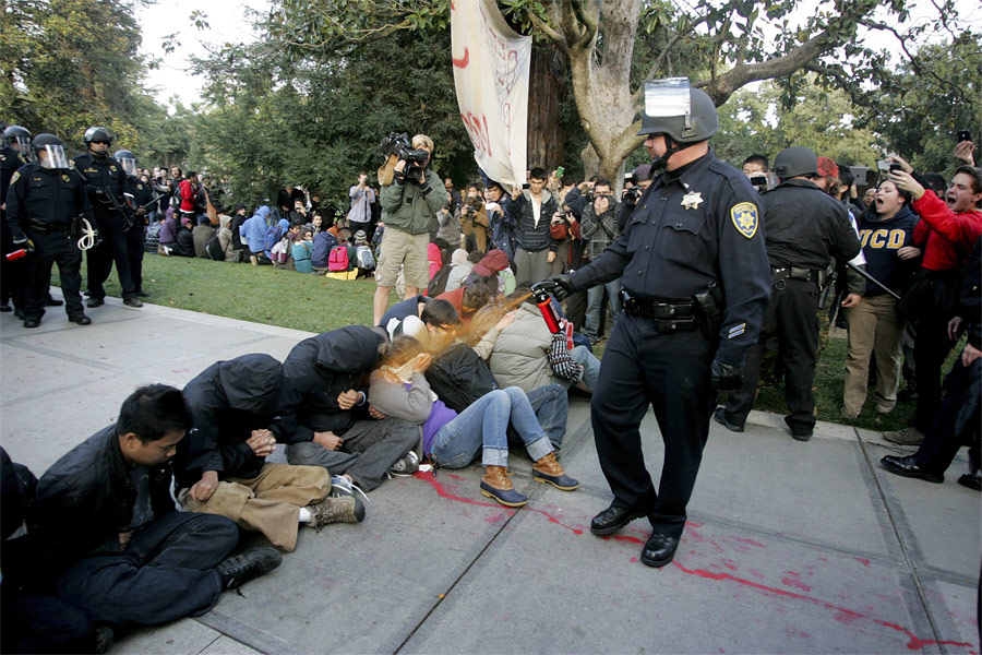 Полицейский распыляет перцовый газ в лица студентам. © Brian Nguyen/Reuters