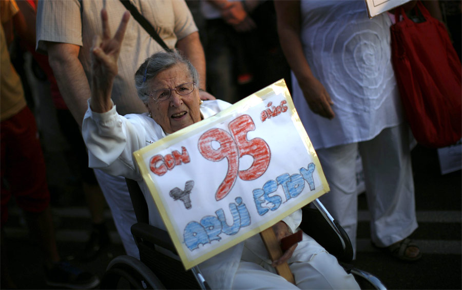 95-летняя Мария Буэно участвует в акции протеста против финансовой системы в Малаге, Испания. На баннере написано: «Мне 95 и я здесь». © Jon Nazca/Reuters