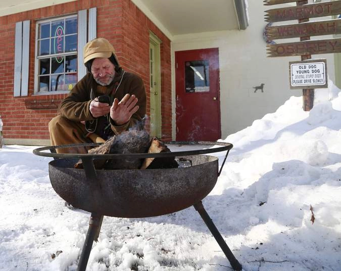 Брэдли Смит греется у огня в ожидании оборудования для уборки снега.