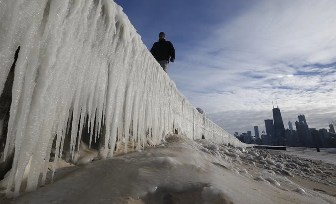 Человек идет по замерзшей стене на пляже в Чикаго.