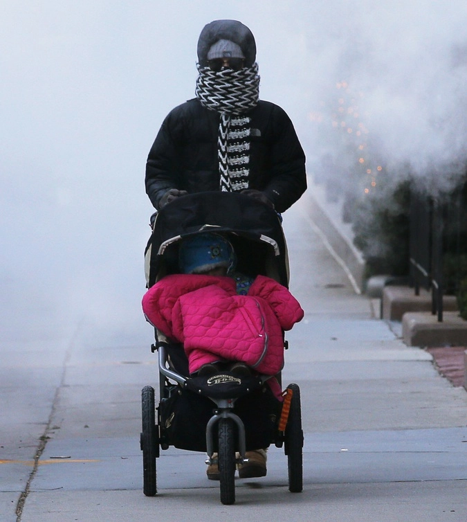 Женщина везет коляску через облако пара в Бостоне.
