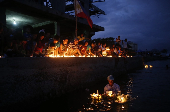 Выжившие зажигают свечи, чтобы почтить память жертв.