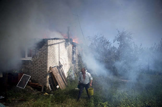 Местный житель ликвидирует пожар в одном из домов в станице Луганская