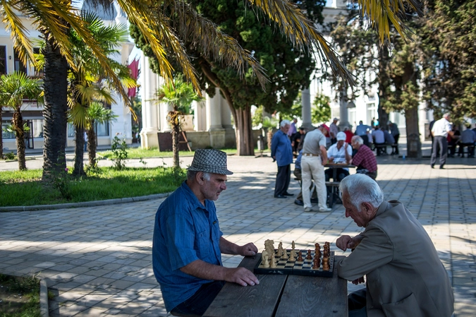 Пожилые люди играют в шахматы на одной из улиц Сухума.