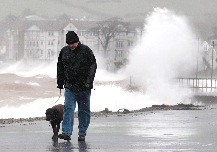 Человек с собакой во время урагана в шотландском городе Ларгс. © David Moir/Reuters