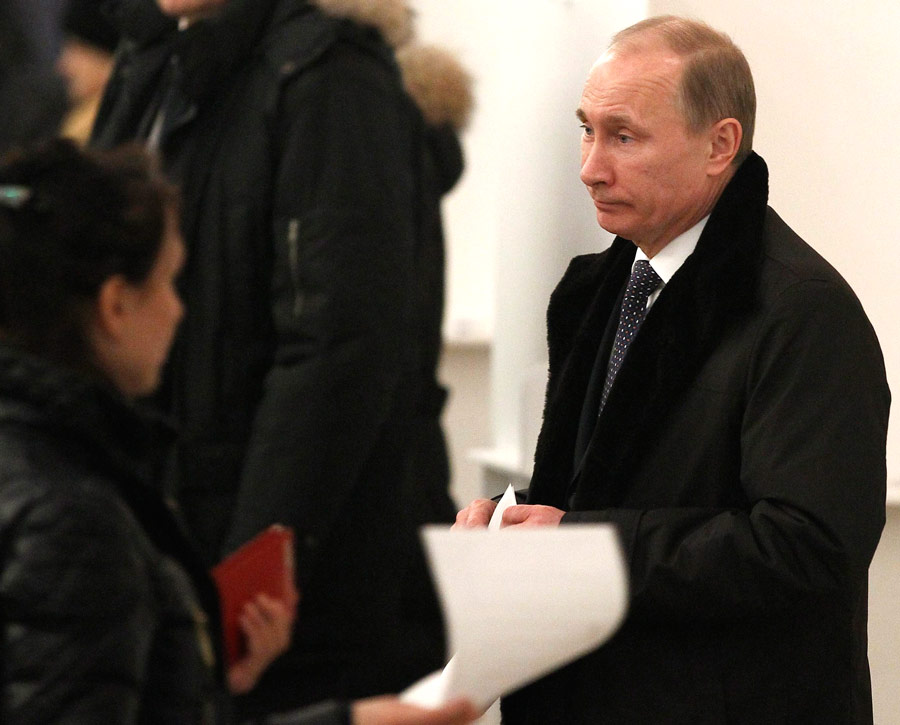 Владимир Путин держит бюллетень перед голосованием на одном из избирательных участков в Москве. © Grigory Dukor/Reuters