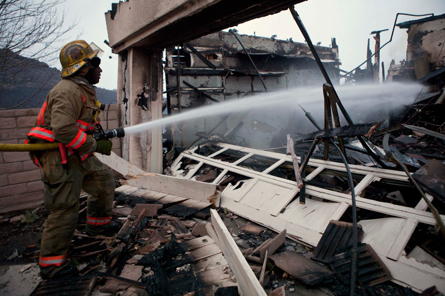 Сотрудник пожарной службы во врем тушения горящего дома из-за лесных пожаров в Рино© Max Whittaker/Reuters