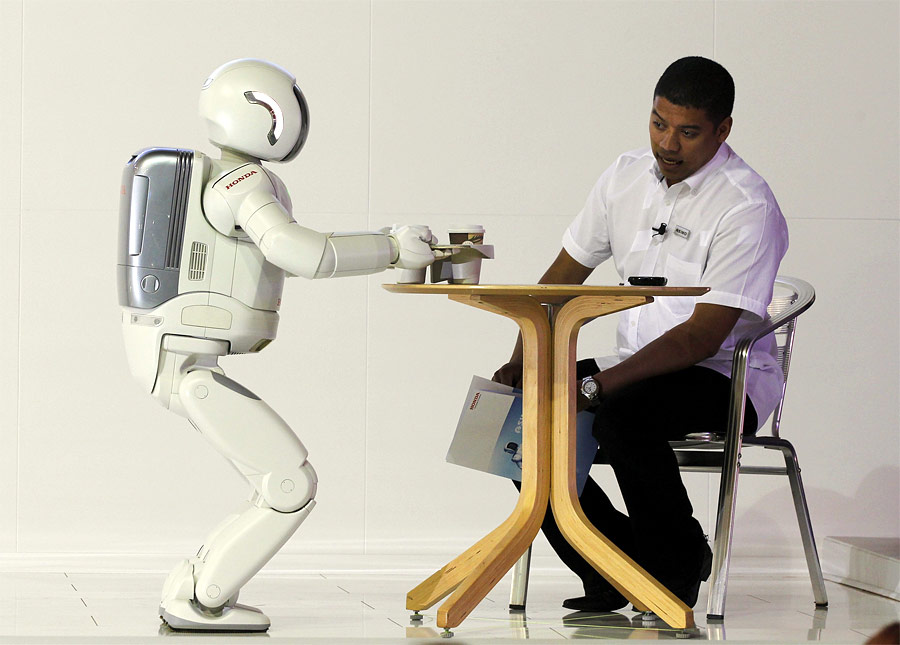 Робот ASIMO, созданный японской компанией Honda, подносит чай посетителю Международного автосалона в Йоханнесбурге. © Siphiwe Sibeko/Reuters