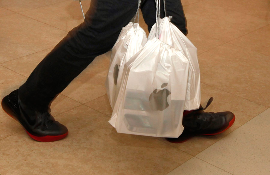 Человек несет пакеты с iPhone 4S после начала продаж в Гонконге. © Bobby Yip/Reuters