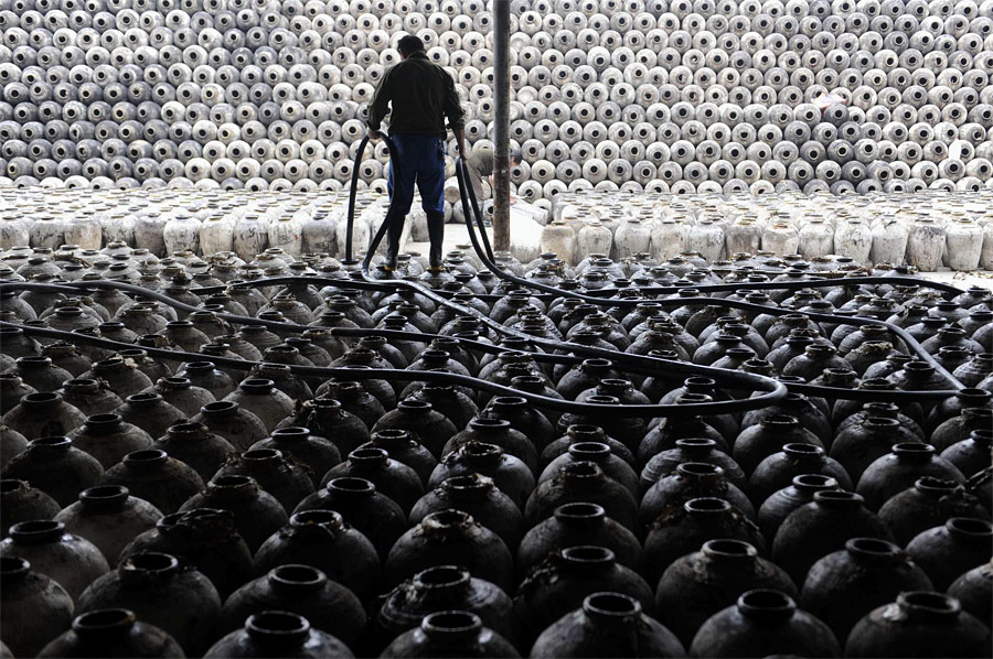 Китайский рабочий моет глиняные сосуды для хранения рисового вина на заводе в Шаосине, провинция Чжэцзян. © Lang Lang/Reuters